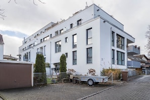 Un edificio moderno de varios pisos con tejado plano, ventanas amplias y el número '21' visible en la fachada.