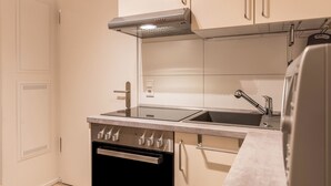 Una cucina compatta con piano cottura, forno, lavello e pensili in acciaio inossidabile.