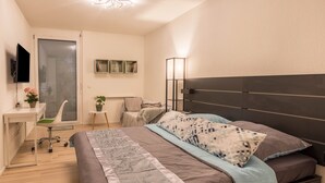Una camera da letto con un letto, una scrivania, una sedia e una TV a muro.