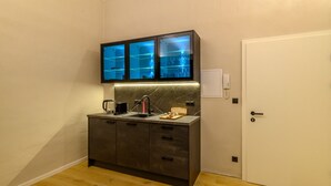 Une petite cuisine équipée avec un téléviseur encastré, une machine à café et un petit plan de travail.