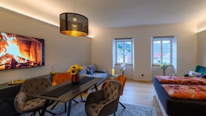 Ein modernes Wohnzimmer mit Essbereich, Kamin und großen Fenstern.