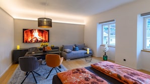 Ein modernes Wohnzimmer mit einer Couch, einem Esstisch und einem an der Wand montierten Fernseher.