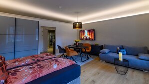 Ein modernes Wohnzimmer mit einer Couch, einem Esstisch mit Stühlen, einem Bett mit floralem Bettzeug und einem Kamin.