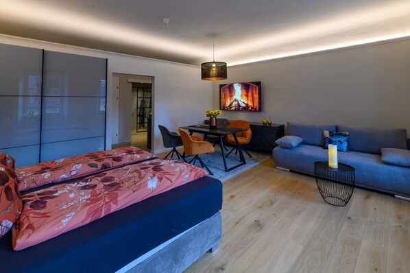 Una sala de estar moderna con un sofá, una mesa de comedor con sillas, una cama con ropa de cama floral y una chimenea.