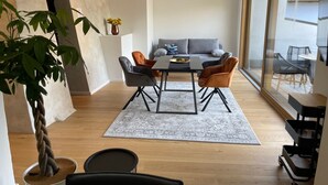 Ein stilvolles Wohnzimmer mit Essbereich, einer Couch und einem großen Fenster.