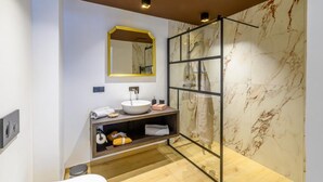 Une salle de bain moderne avec un mur en marbre, une douche en verre, un lavabo blanc et un meuble-lavabo en bois.