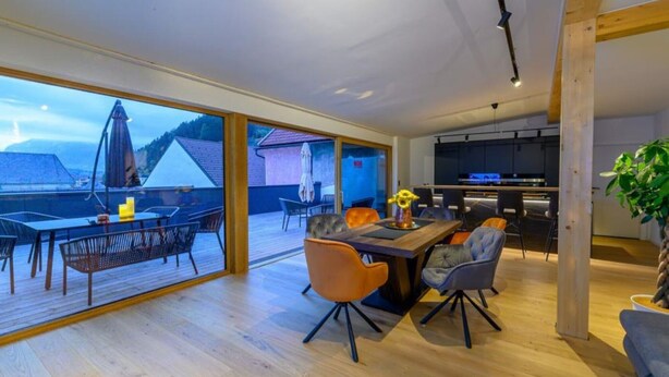 Un intérieur moderne comprenant un coin repas, une cuisine et de grandes fenêtres donnant sur un paysage montagneux.