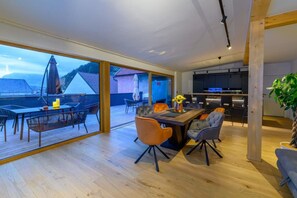 Um interior moderno com área de jantar, cozinha e grandes janelas com vista para uma paisagem montanhosa.