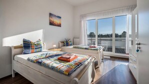 Een slaapkamer met twee bedden, een raam met uitzicht en een nachtkastje met een lamp.