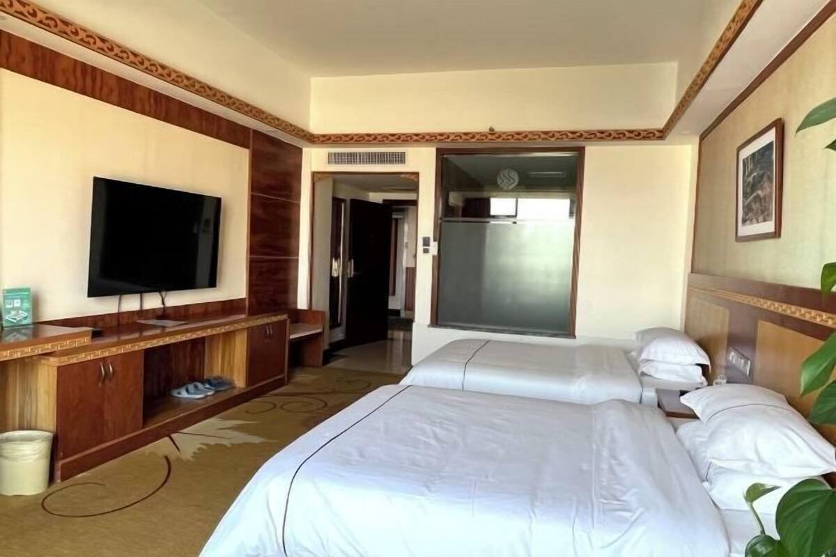 A hotel room with two beds, a TV, a wardrobe, and a bathroom door.