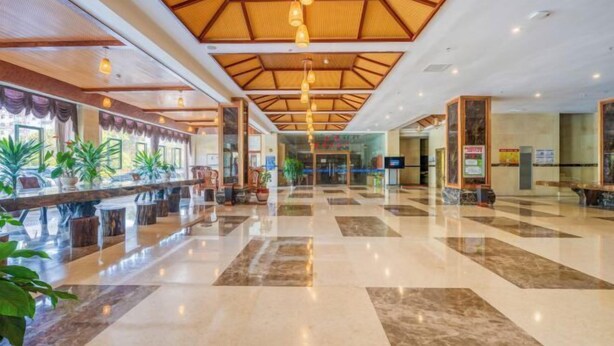 Eine geräumige Lobby mit Schachbrettmuster-Boden, Holzbalkendecke und hängenden Pendelleuchten.