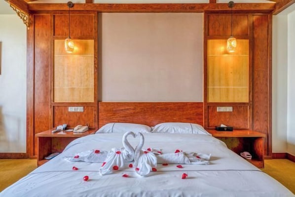 A hotel room with a large bed, wooden headboard, bedside tables, and wall-mounted lamps. - Yunti Hotel (Honghe County)