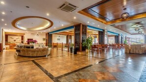 Eine großzügige Lobby mit Empfangsschalter, Sitzgelegenheiten und großen Fenstern.
