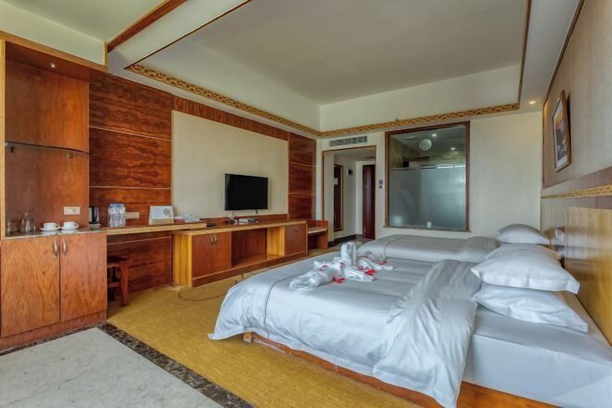 A hotel room with a bed, a desk, a television, and a bathroom door.