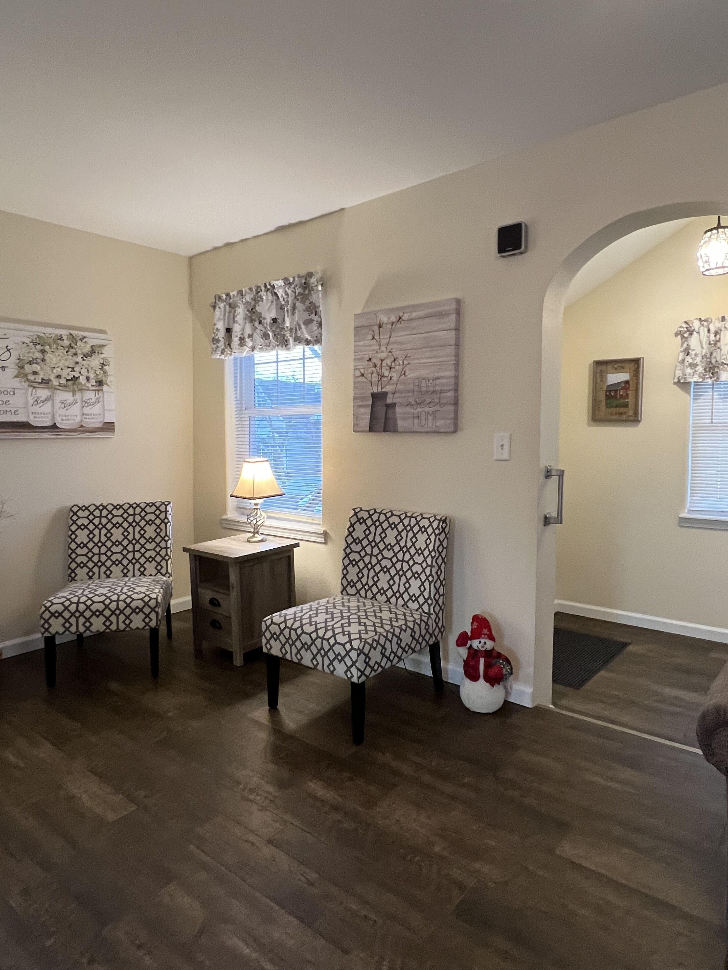 Una sala de estar con dos sillones estampados, una mesita con una lámpara y un jarrón decorativo.