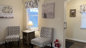 Una sala de estar con dos sillones estampados, una mesita con una lámpara y un jarrón decorativo.