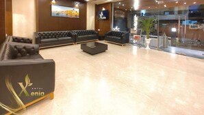 A hotel lobby with leather sofas, a coffee table, a chandelier, and a TV screen. - HOTEL XENIA (Varanasi)