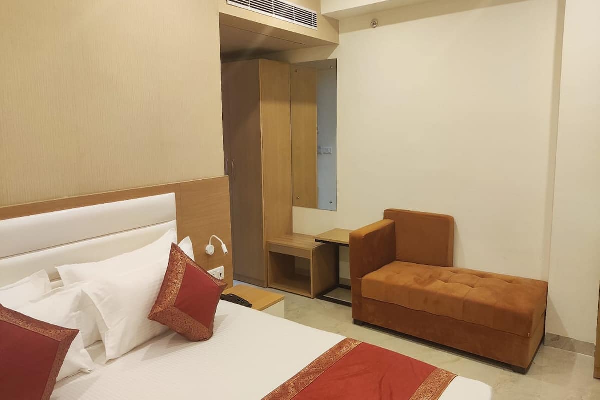 A hotel room with a bed, a sofa, a small table, and a mirror.