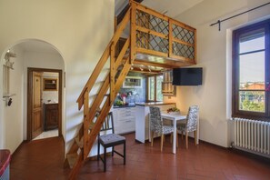 A kitchen with a wooden staircase, a dining area with two chairs, and a window with a view. - Atelier Bellesi - Sweet Dreams in Florence (Firenze)