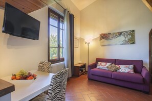 A living room with a television, a sofa, a window with curtains, a painting, and a fruit bowl. - Atelier Bellesi - Sweet Dreams in Florence (Firenze)