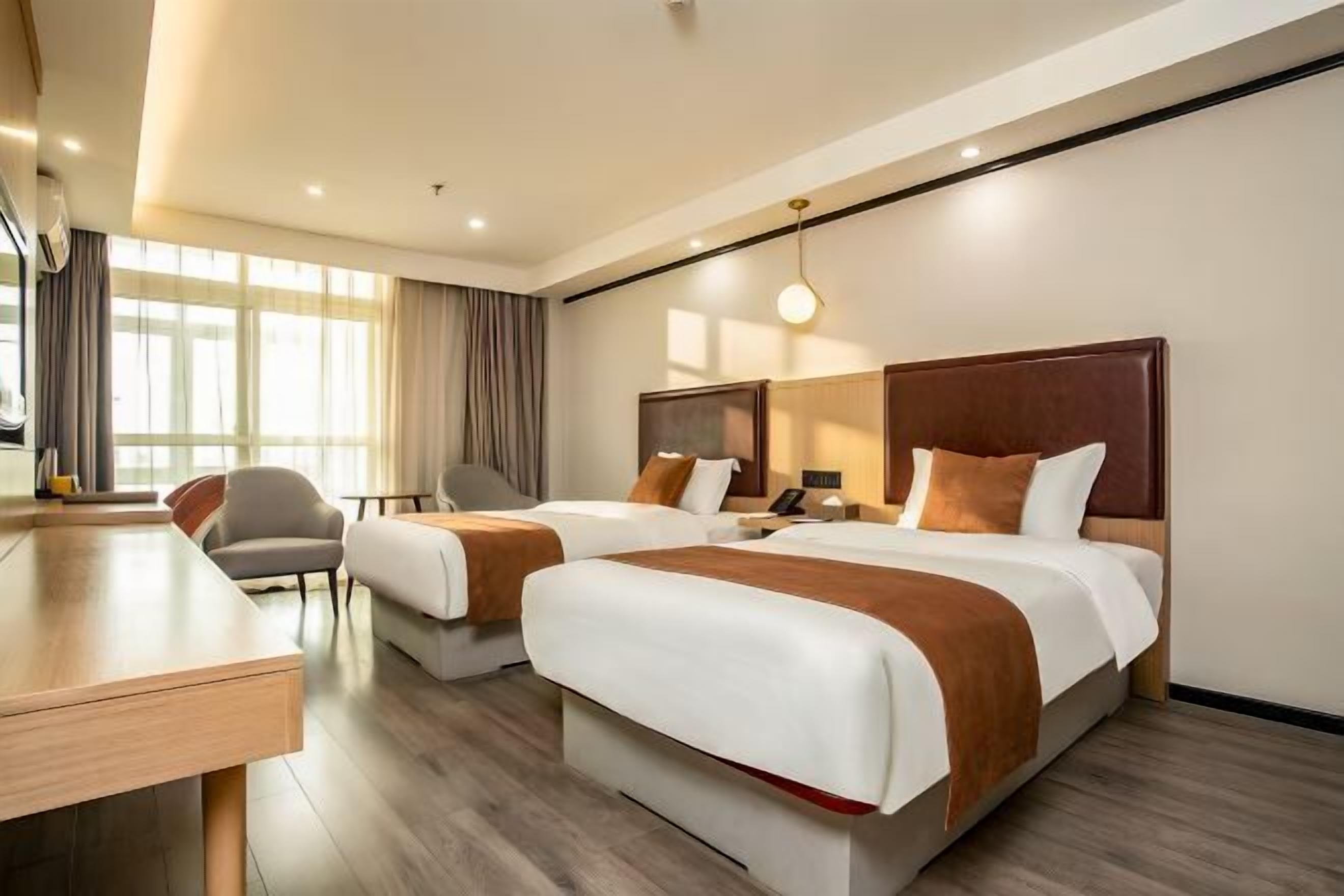 A hotel room with two beds, a desk, and a chair.