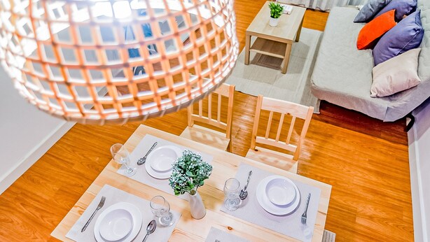 Comedor con una mesa de madera dispuesta para cuatro personas, rodeado de sillas.