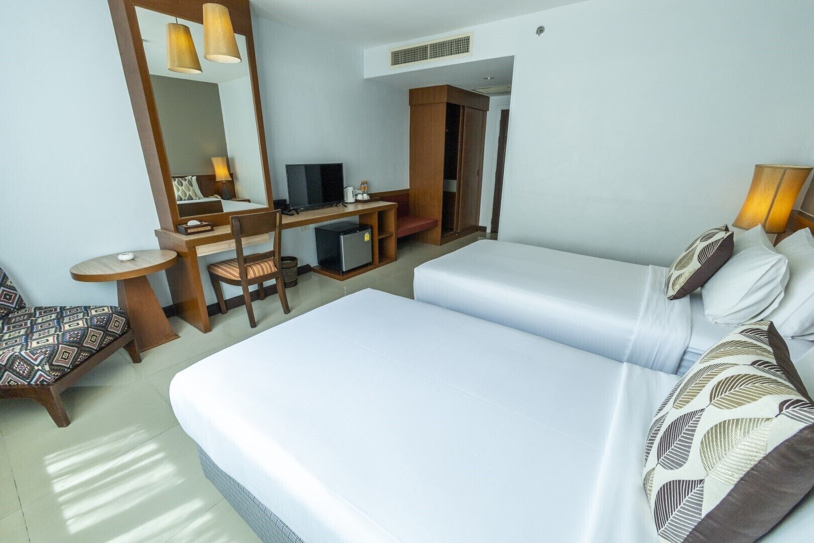 A hotel room with a bed, a desk with a computer, a chair, and a television.