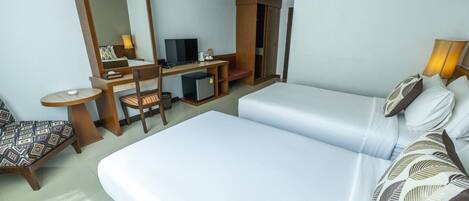 Una habitación de hotel con cama, escritorio con computadora, silla y televisor.