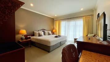 Una habitación de hotel con cama, mesitas de noche, escritorio, silla y un espejo grande.