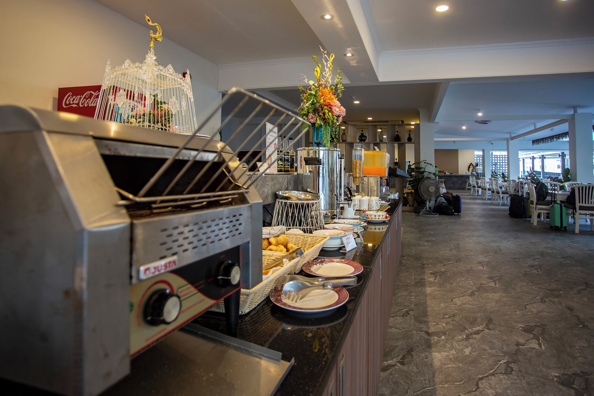 A buffet setup with a Coca-Cola sign, a decorative birdcage, and a variety of food items on the counter.