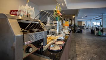 A buffet setup with a Coca-Cola sign, a decorative birdcage, and a variety of food items on the counter.