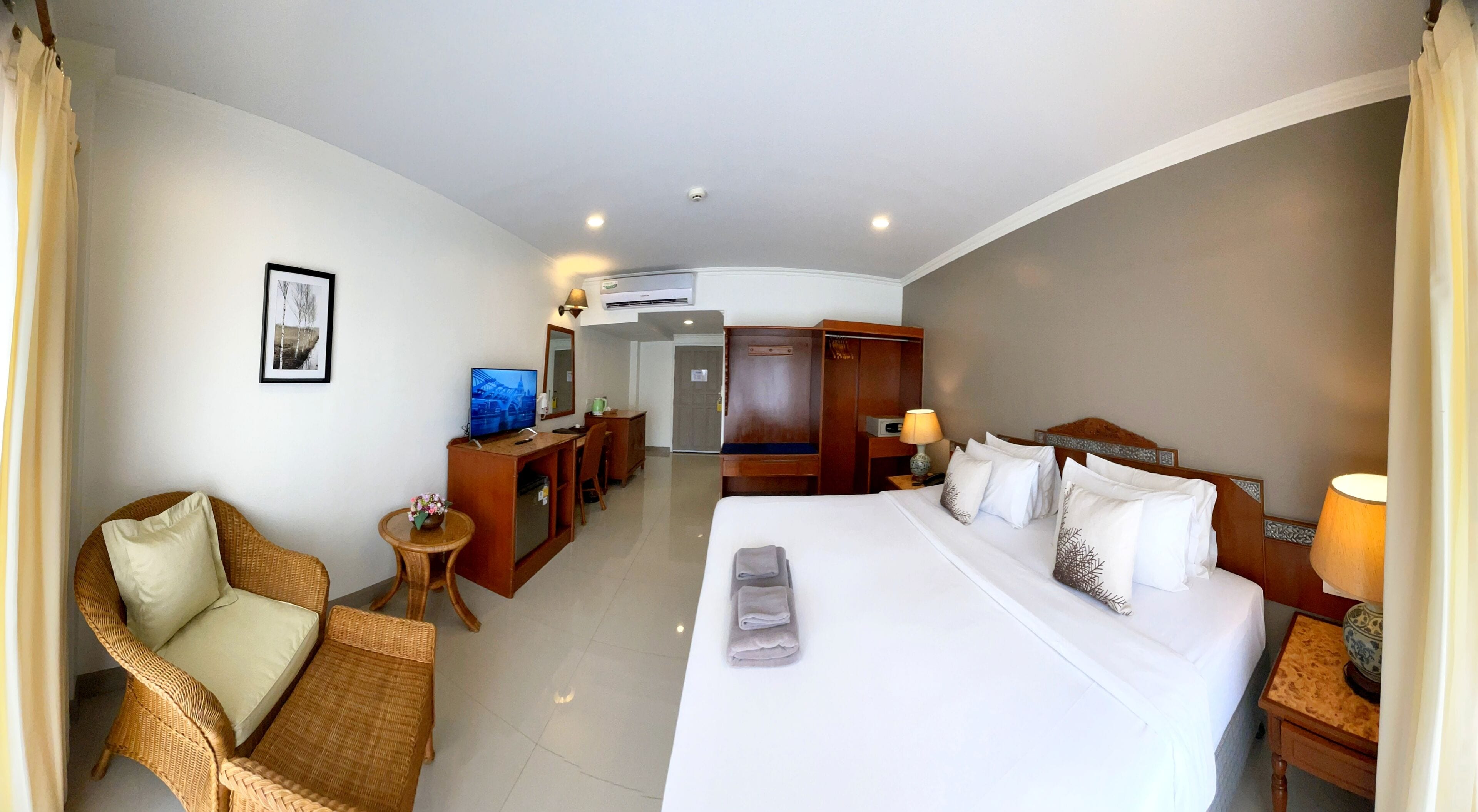 A hotel room with a bed, a desk, a chair, a television, and a wardrobe.
