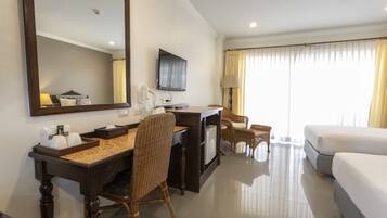 Una habitación de hotel con una cama, un escritorio con una silla, un televisor y un espejo grande.