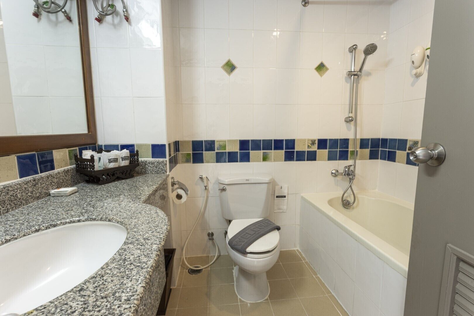 Um banheiro com bancada de granito, vaso sanitário, banheira e chuveiro.