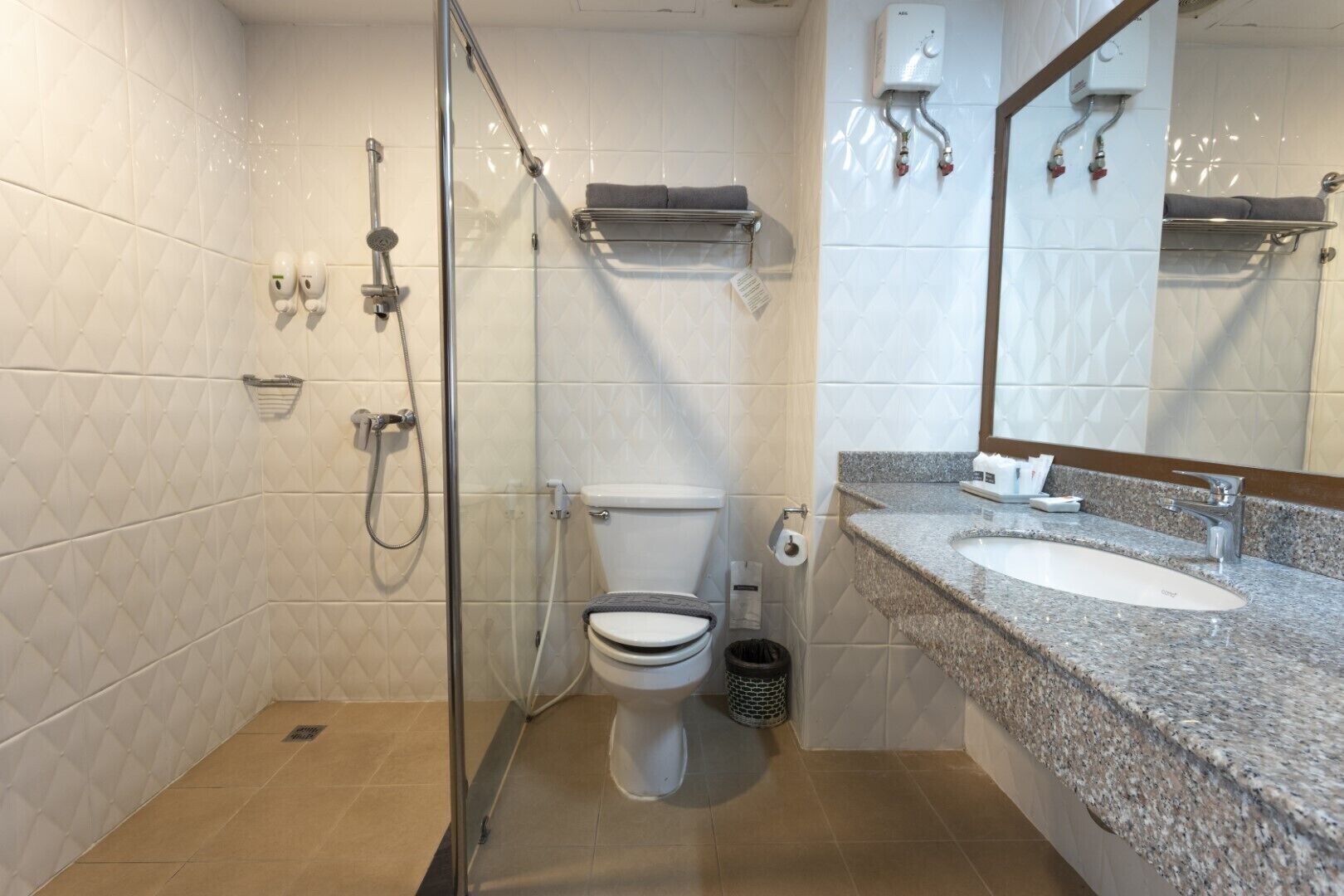 A modern bathroom with a glass-enclosed shower, a toilet, and a granite countertop sink.