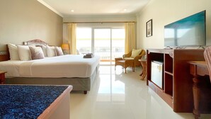 A hotel room with a bed, a TV, a desk, and a balcony with a view. - Sabai Sabana (Pattaya)