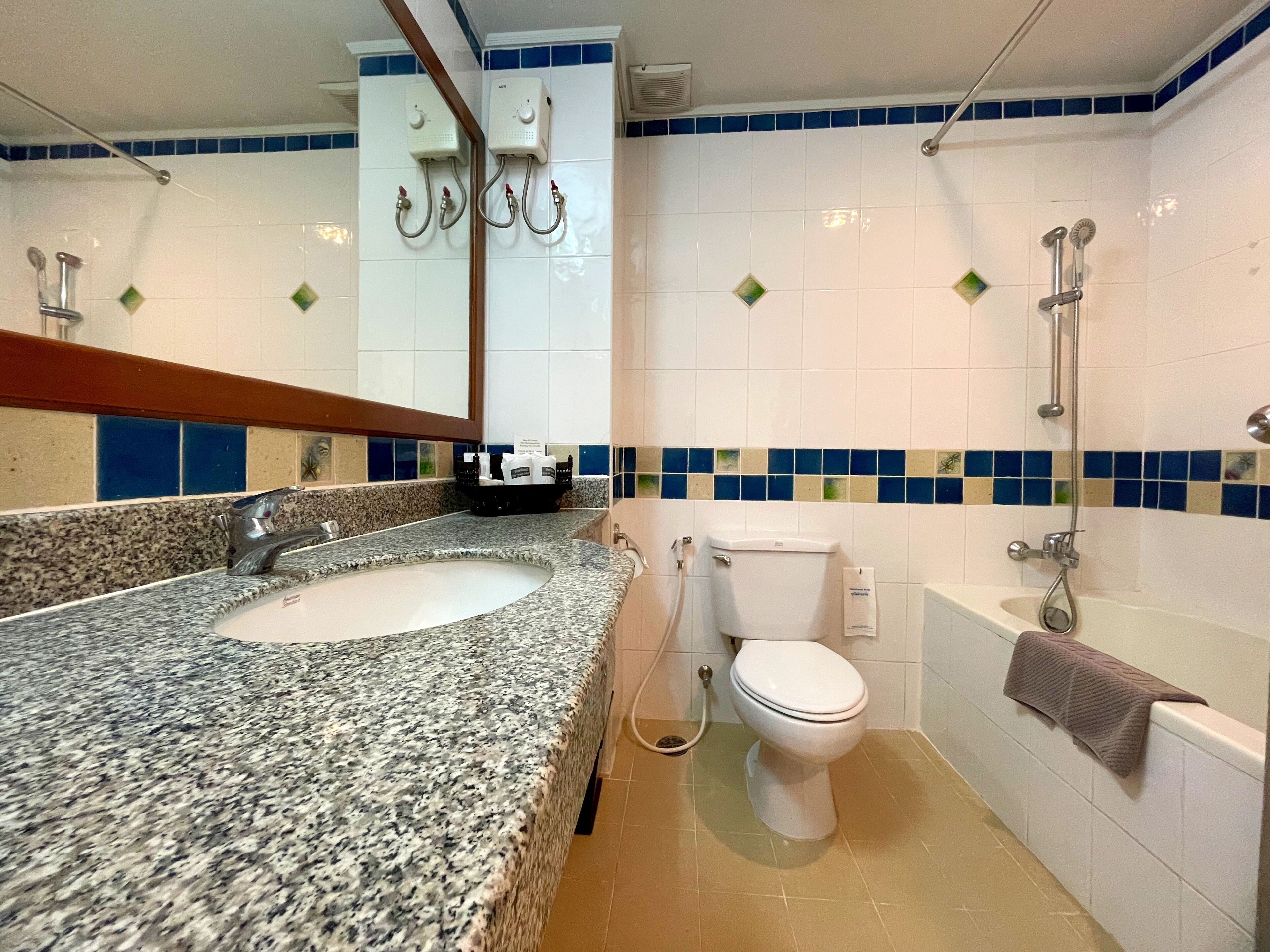 Ein Badezimmer mit einem Granitwaschbecken, einer Toilette und einer Badewanne.