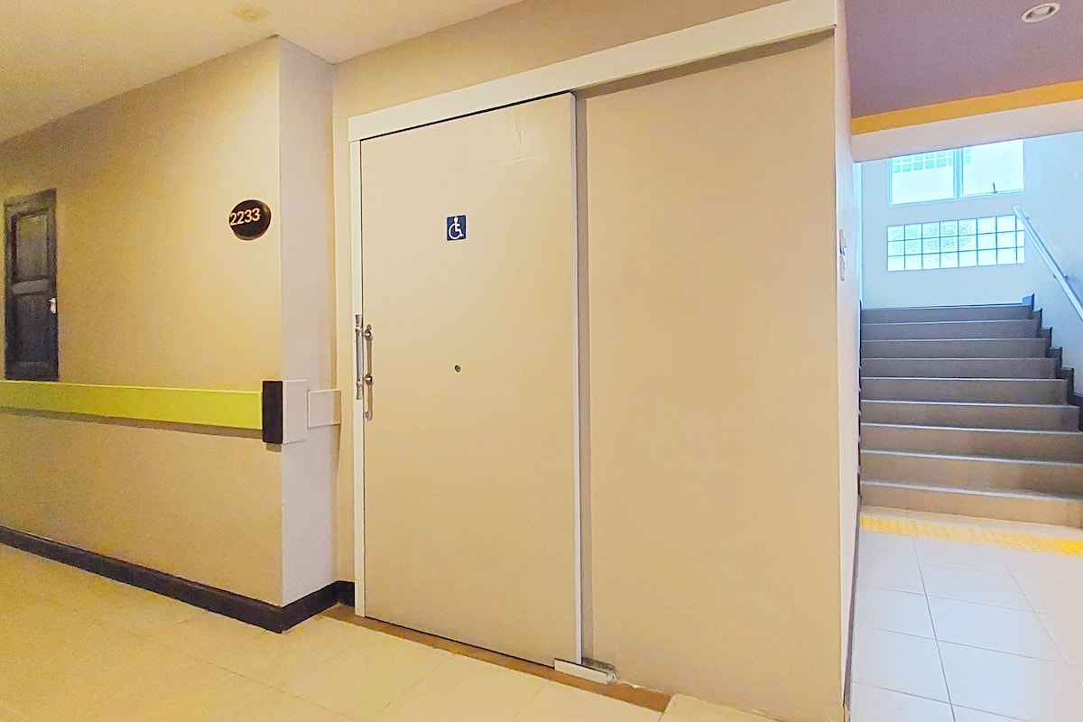 A hallway with a double door, a wheelchair accessibility sign, and a staircase with a handrail.