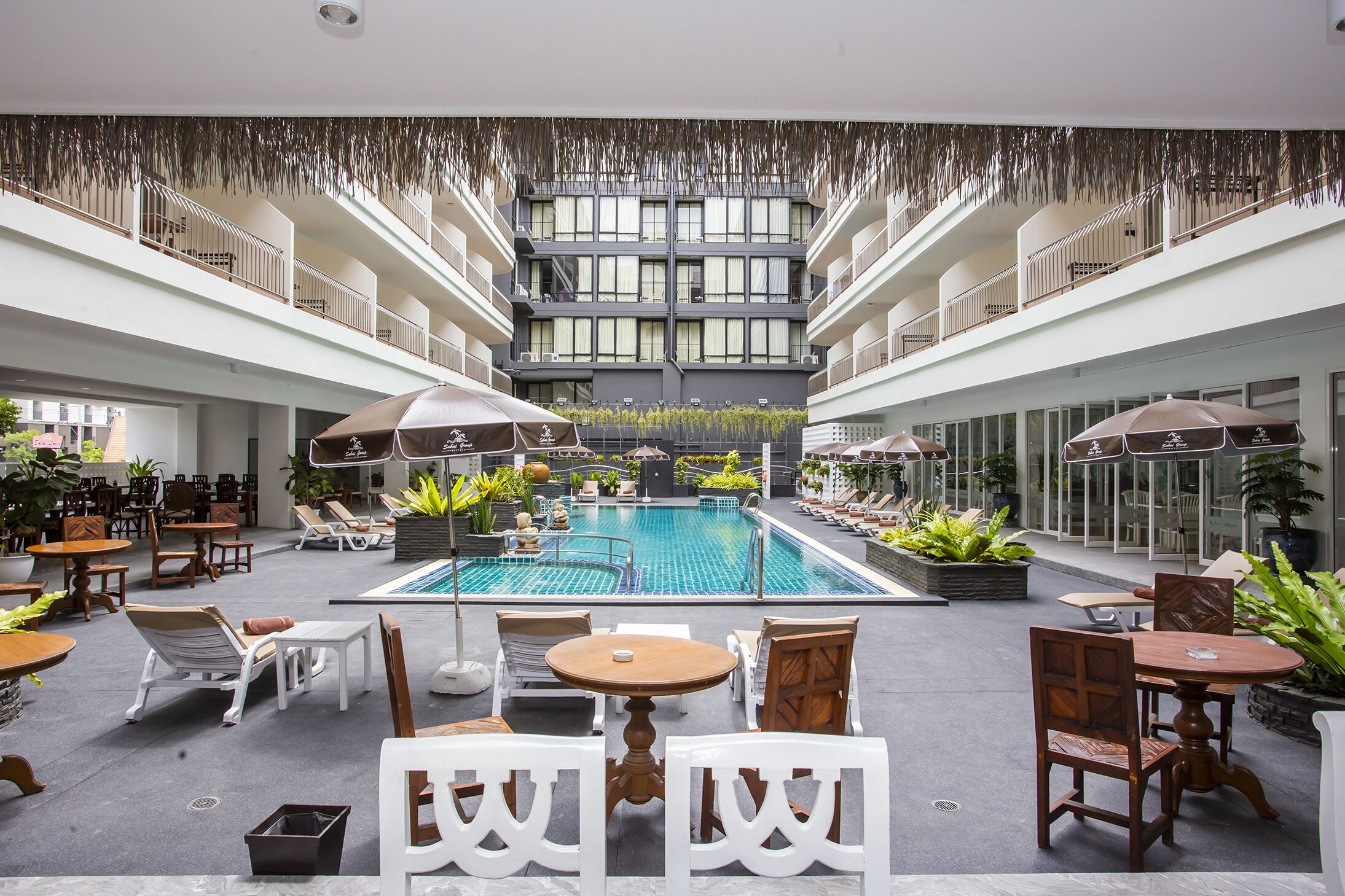 Zona de piscina en la azotea con diversas opciones de asientos y vista al interior del edificio.