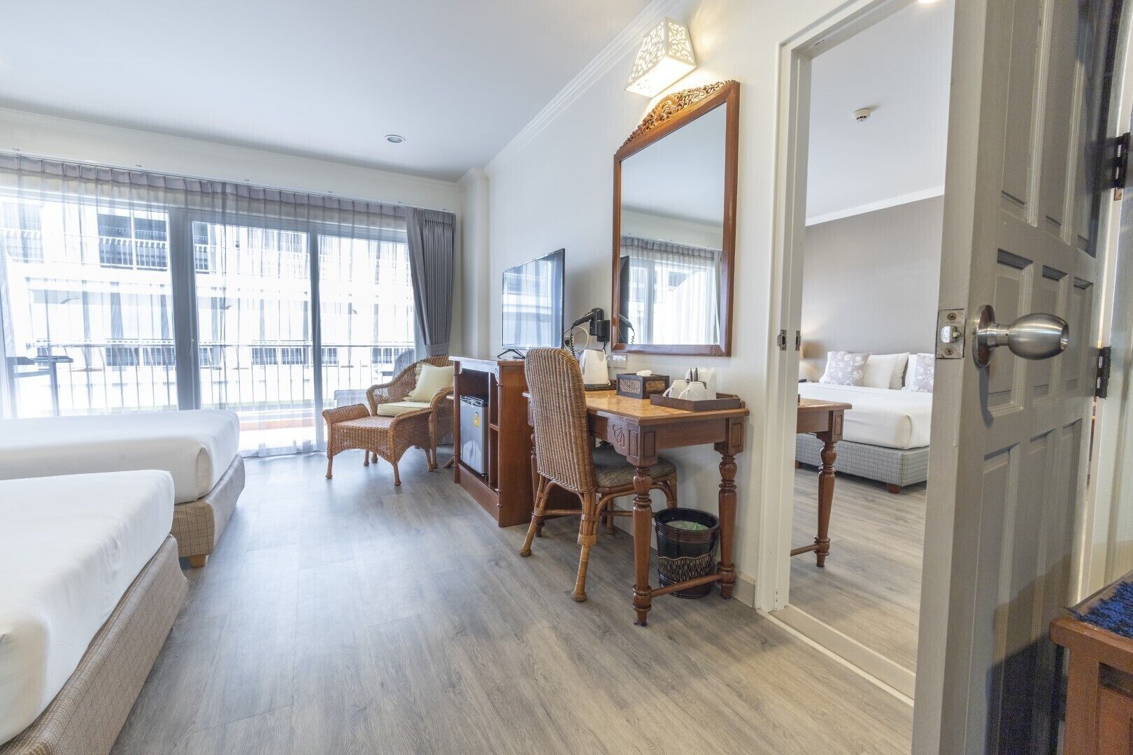 Habitación de hotel con cama, escritorio con silla, un espejo grande y vistas al exterior.