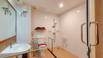 Un baño moderno con lavamanos, inodoro y ducha blancos. Incluye una barandilla y un perchero para toallas.