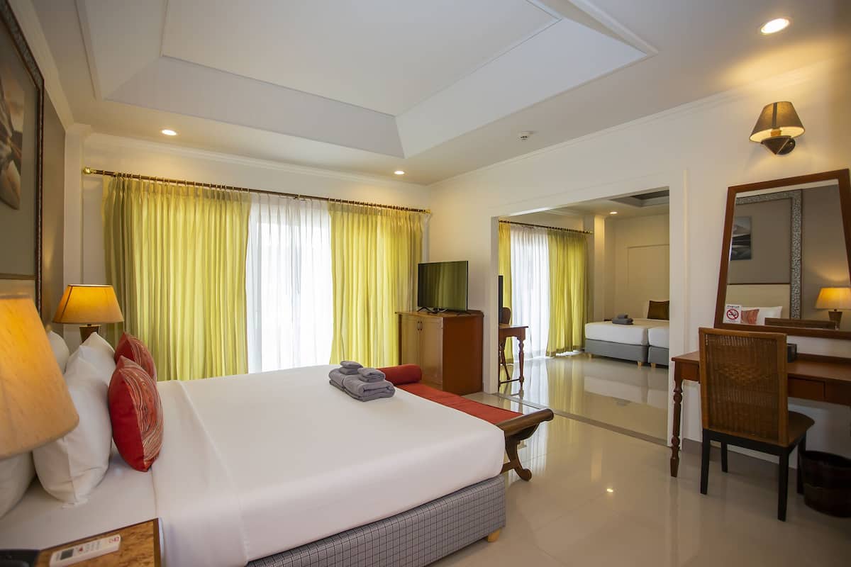 A hotel room with a large bed, a desk, a chair, and a television.