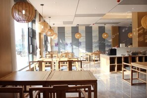Un restaurant avec des tables et des chaises en bois, un comptoir et des luminaires suspendus.