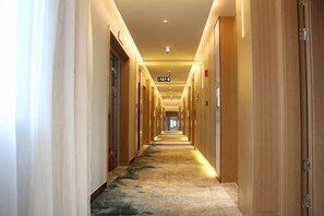 A long, narrow hotel corridor with doors on both sides, a carpeted floor, and overhead lighting. - Qingmu Select Hotel (Liyang Tianmu Lake Scenic Area) (Liyang)