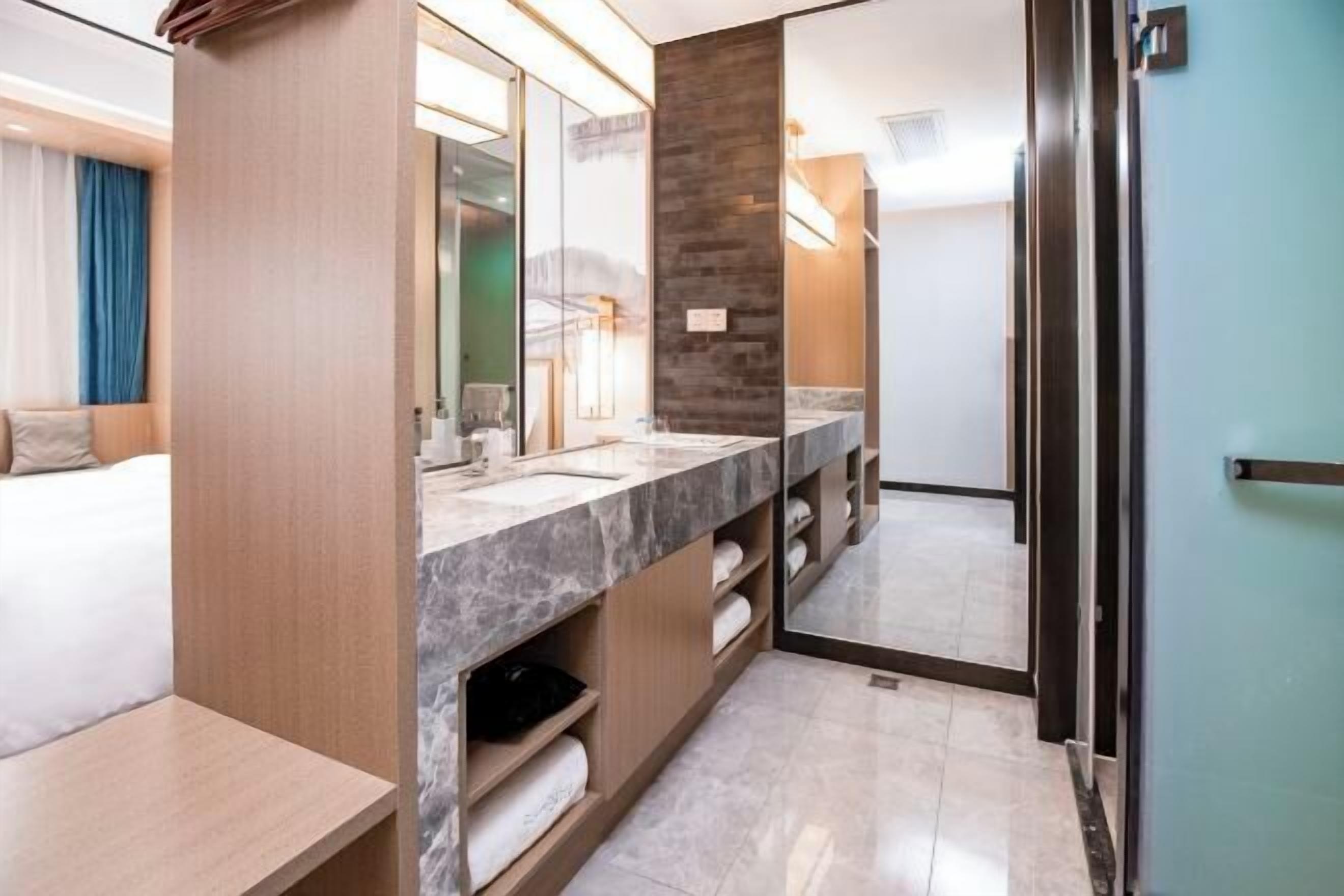 Une salle de bain moderne avec un comptoir en marbre, un grand miroir et un meuble-lavabo en bois.