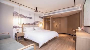 A modern hotel room with a large bed, bedside tables, a desk, and a wardrobe.