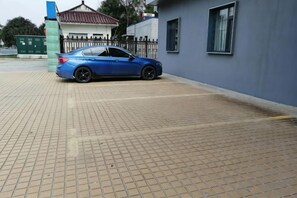 A blue car parked on a paved area with a building in the background. - Qingmu Select Hotel (Liyang Tianmu Lake Scenic Area) (Liyang)