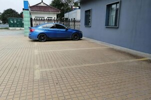 Un coche azul estacionado en una zona pavimentada, con un edificio al fondo.