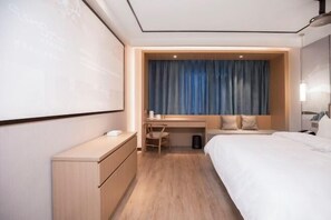 A hotel room with a bed, a desk, a chair, a wardrobe, and a large screen. - Qingmu Select Hotel (Liyang Tianmu Lake Scenic Area) (Liyang)