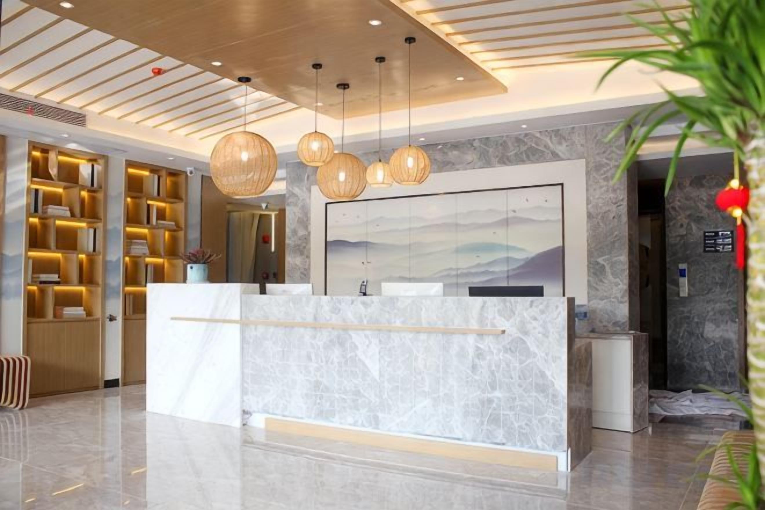 A reception area with a marble counter, hanging spherical light fixtures, and a bookshelf filled with books.